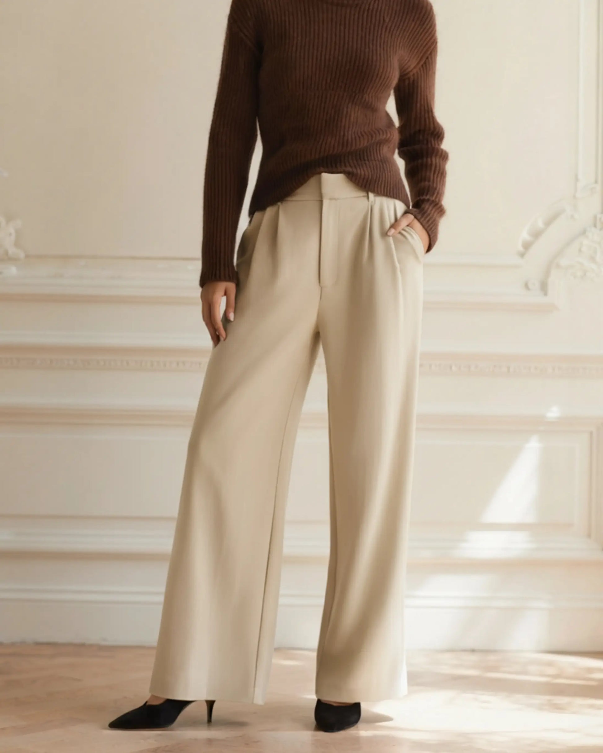Women's beige high-waist tailored wide-leg trousers with front pleats, styled with brown strappy sandals