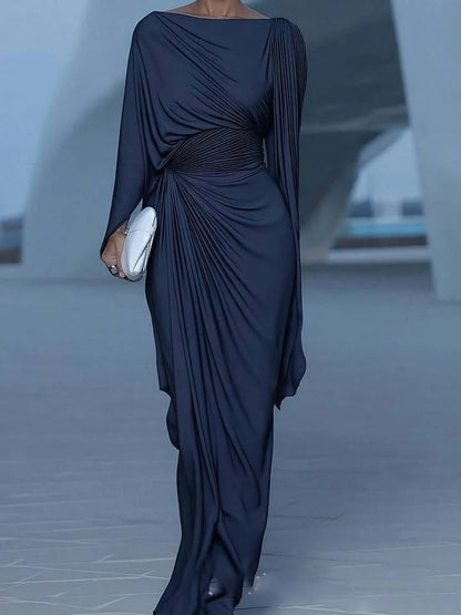 Elegant woman wearing a midnight blue draped evening dress with asymmetric gathers in a modern architectural setting Vohran UK.