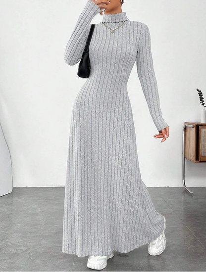 Woman wearing Vohran ribbed high-neck knit maxi dress with long sleeves and high neckline Vohran UK.