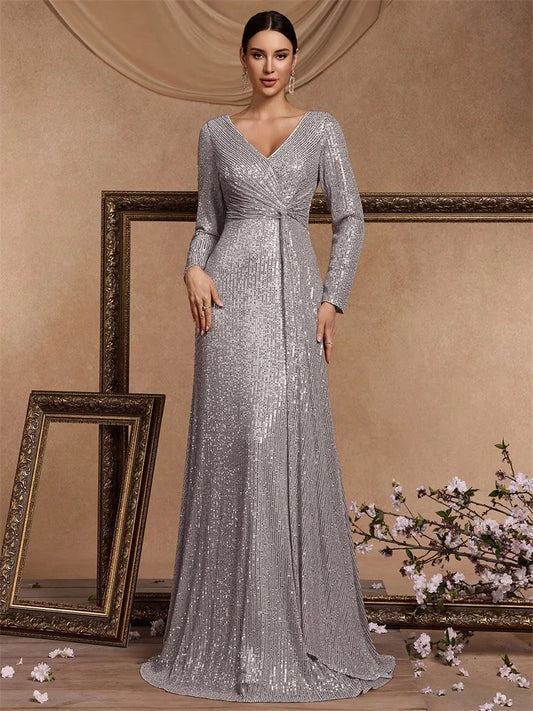 Elegant woman wearing a silver sequined long-sleeve evening gown with a draped waist in a classic studio setting Vohran UK.